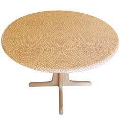 a round table with an intricate design on it's top and wooden legs, against a white background