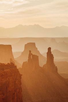 the sun is setting over canyons and rocks in the desert, with mountains in the background