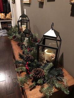 two lanterns and some pine cones on a table