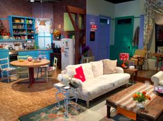 a living room filled with furniture next to a kitchen and dining room table in front of a blue door