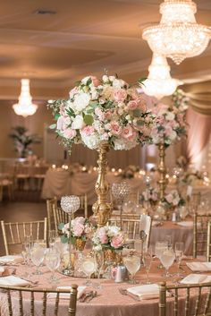 the centerpieces on this table are filled with pink and white flowers, while gold candelabra stands above them