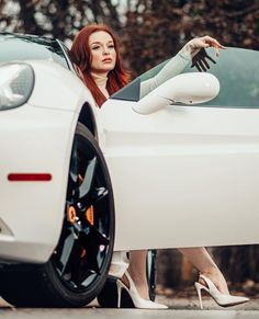 a woman sitting on the hood of a white sports car