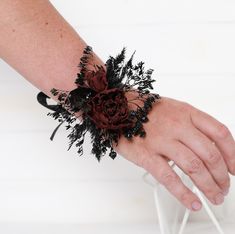 a person's hand with a flower on it and some black flowers in the middle