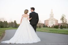 a bride and groom are walking down the road together in front of a large church