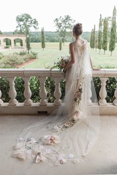 a woman in a wedding dress standing on a balcony with flowers all over the floor