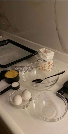 an assortment of ingredients are sitting on the counter top, including eggs and flour in bowls