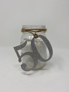 a glass jar filled with sand next to a tag that says 50 on the front