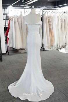 a white wedding dress is on display in a room with other dresses and gowns