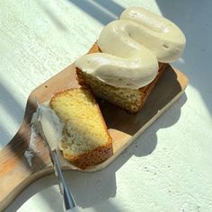 a wooden cutting board topped with two slices of cake covered in frosting next to a knife