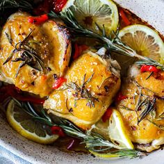 chicken with lemon and rosemary garnish in a white bowl