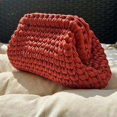 an orange woven purse sitting on top of a bed