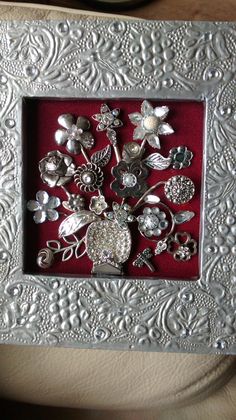 there is a silver brooch set in a red box