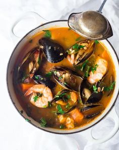 a pot filled with seafood and mussels on top of a white table cloth