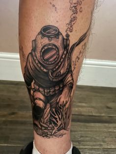 a man's leg with a diving diver tattoo on it and an octopus in the water