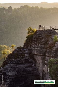 two people standing on top of a cliff