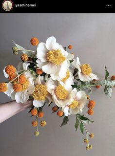 white and yellow flowers are being held by someone's hand