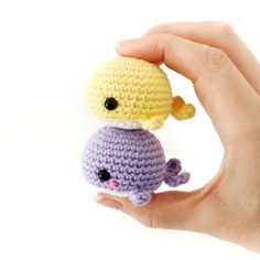 a hand holding a small crocheted toy in the shape of a whale and an octopus