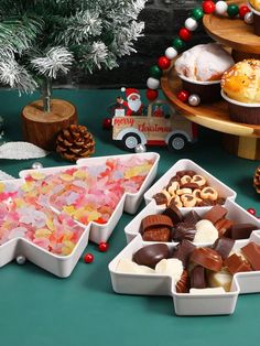 several trays filled with different types of candy on a table next to christmas decorations