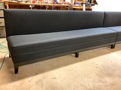 a gray couch sitting on top of a floor next to a wooden shelf filled with items