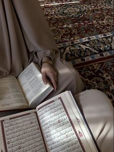 a person sitting down with an open book in their lap and hands on the pages