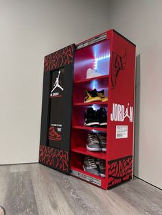 a red and black display case with shoes in it next to a wall mounted basketball shoe rack