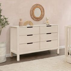 a baby's room with a crib, dresser and mirror on the wall