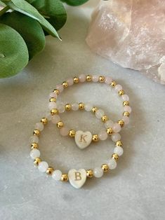 - The cutest little girl initial bracelet. This delicate and dainty initial beaded bracelet has a freshwater shell heart initial with 18k gold filled and gemstone beads. A perfect and sweet personalized new baby gift or toddler bracelet. Beaded on high quality stretch cord and secured. - 4mm 18k gold filled beads   5mm gemstone beads ( white jade, rose quartz) ‼️Young children MUST be supervised at all times while wearing jewelry. Contains small parts that could be a potential choking hazard. Jewelry should always be removed during sleep. Never leave young children unattended with our products. Supervision is required. It is at the customers discretion for the use of our products.  - Each purchase is sent in a velvet drawstring jewelry bag, making the perfect 1st birthday personalized gift Personalized Dainty Charm Bracelet With Round Beads, Dainty Adjustable Name Bracelet With Initials, Dainty Beaded Name Bracelet, Personalized Adjustable Dainty Pearl Bracelet, Personalized Pink Dainty Beaded Bracelets, Dainty Letter Beads Beaded Bracelets For Birthday, Dainty Beaded Bracelets With Letter Beads For Birthday, Dainty Letter Beads Bracelet For Birthday, Dainty Beaded Bracelets For Birthday