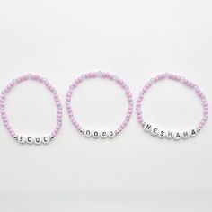 This exquisite Neshama bracelet set features three delicate bracelets crafted with lavender glass beads. Each bracelet bears the word "נשמה" in Hebrew letters, "Neshama" in English, and "Soul" in English. These elegant and meaningful bracelets blend traditional design with a contemporary touch, embodying the essence of spirituality and style. Hebrew Bracelet, Meaningful Bracelets, Judaica Jewelry, Hebrew Letters, Judaica Gifts, Jewish Jewelry, Bracelet Crafts, Traditional Design, Bracelet Set