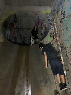 two skateboarders are riding down a ramp with graffiti on the walls