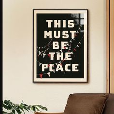 this must be the place poster hanging on wall next to chair and potted plant