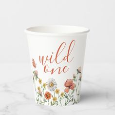 a paper cup with wild one written on the side and flowers painted all over it