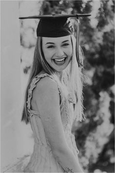 a young woman wearing a graduation cap and gown smiles at the camera while posing for a black and white photo