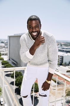 a man standing on top of a balcony next to a building with his hands in his pockets