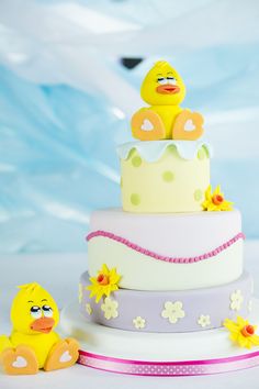 a yellow rubber ducky sitting on top of a white and pink cake with flowers