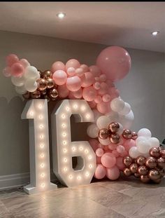 a large balloon arch with the number sixteen surrounded by balloons and streamers in pink, gold and white