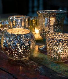 several lit candles sitting on top of a table next to glass bowls and cups with holes in them