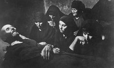 black and white photograph of people in bed with one person holding the head of another