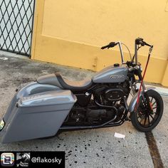 a motorcycle parked on the street next to a yellow building with a black handlebar