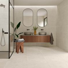 a bathroom with two sinks, mirrors and a shower head mounted to it's wall