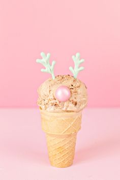 an ice cream cone with reindeer antlers on it's head and pink frosting