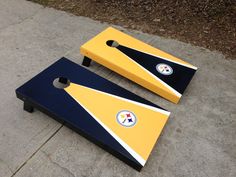 two yellow and blue cornhole boards sitting on top of a cement ground next to each other