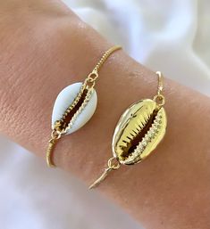 Features genuine Cowrie Shells, dipped in gold plating and affixed to a 14k gold filled box style chain. The bracelet is fully adjustable for a customized fit. Simply slide the gripper disc to your liking. It holds securely. Choose from White with gold trim or All gold. (Bamboo Cuff bracelet shown layered is available separately in the shop) Makes a great gift! I have Cowrie Necklaces available in the shop as well, so take a look around! *Please avoid showering, swimming or spraying perfume with Adjustable Nickel-free Yellow Gold Jewelry, Trendy Resizable Gold Jewelry, Gold Friendship Bracelets With Adjustable Length, Gold Bracelets With Adjustable Length As Gift, Gold Bracelets With Adjustable Length For Gift, Dainty White Resizable Jewelry, Gold Jewelry With Adjustable Length For Friendship, Gold Adjustable Jewelry For Friendship, Gold-tone Adjustable Jewelry As Gift