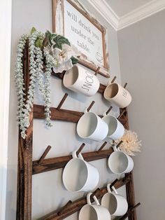 coffee cups are hanging on a wooden ladder