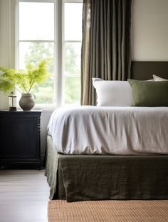 a bed sitting next to a window with curtains on top of it and a plant in the corner