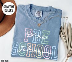 a blue t - shirt with the words pride school on it next to some feathers