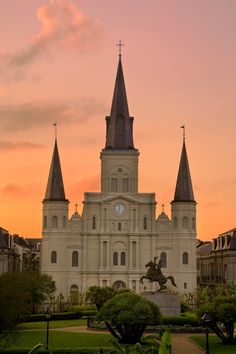 a large white building with two towers and a clock on it's face at sunset