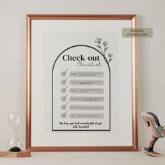 a framed poster with the words check out next to an hourglass on a shelf