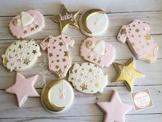 some decorated cookies are laying on a table with gold and pink icing, one has a baby's first year