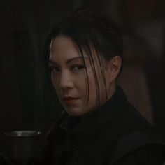 a woman with black hair holding a cup in her hand