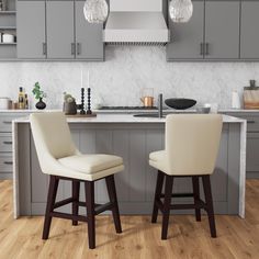 two stools sit in front of a kitchen island with gray cabinets and marble counter tops